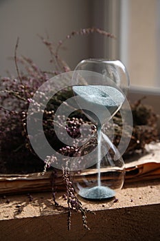 Sandglasses with blue sand, flowers, wood