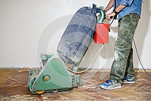 Sanding hardwood floor with the grinding machine. Repair in the apartment