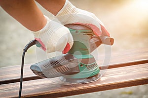 Sanding a wood with orbital sander