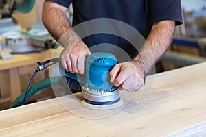 Sanding a wood surface with orbital sander