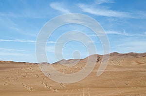 Sands of the desert under bright blue sky with few clouds