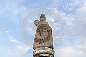 Sandstone bishop with walking stick and bible as symbol for the catholic religion in the Rheingau area in Germany