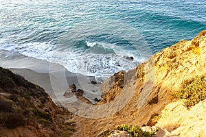 Sandstone path overlooking cliff side, pacfic ocean expanse, and waves on the shore