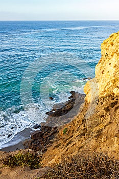 Sandstone path overlooking cliff side, pacfic ocean expanse, and waves on the shore