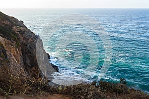 Sandstone path overlooking cliff side, pacfic ocean expanse, and waves on the shore