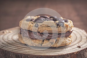 Sanduche de cookies frescos com nutella cremosa em cima de uma tbua de madeira com fundo escuro, isolada