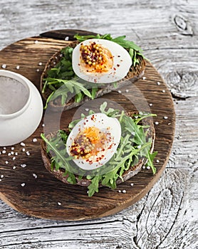 Sandwich with arugula, boiled egg and mustard on a wooden board. Healthy breakfast