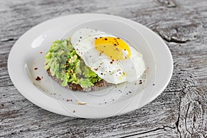 Sandwich with avocado and a fried egg on a white plate