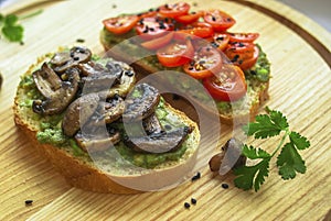 Sandwich with avocado, fried mushrooms spices, cherry tomatoes cilantro black sesame spices on a wooden dish. Vegetarian food