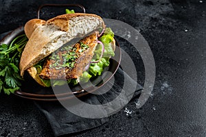 Sandwich balik Ekmek with grilled fillet of mackerel fish, tomatoes, onions and lettuce. Black background. Top view