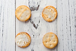 Sandwich biscuits with one piece opend showing the white cream filling on white wood