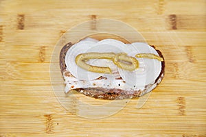 A sandwich of black bread with bacon, onion and mustard on the background of a yellow cutting board. Cooking barbecue