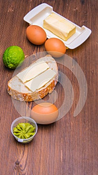 Sandwich ,bread and butter,eggs,lime,butter pancake on a wooden table with space for text,
