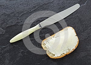 Sandwich, bread with butter and a knife on stone background