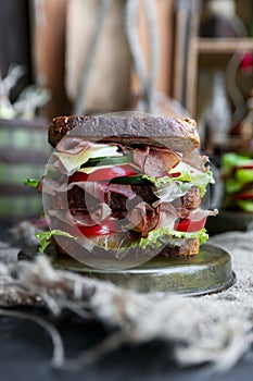 Sandwich with bread, prosciutto, lettuce, tomtatoes, cucumber and cheese in the kitchen