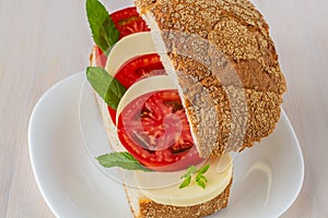 Sandwich from bread, tomato, mozzarella, greens