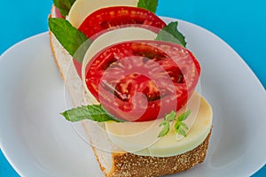 Sandwich from bread, tomato, mozzarella, greens
