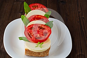 Sandwich from bread, tomato, mozzarella, greens