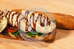 Sandwich of burrata cheese, grilled eggplant, tomato and artisan bread opened on raw wood - Sandwich de queso burrata, berenjenas photo