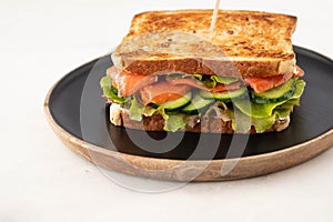 Sandwich with cereals bread and salmon on dark marble background. Copy space.