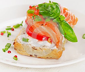 Sandwich with cereals bread and salmon on white plate.