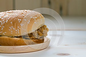 Sandwich with chicken burger on wooden plate.