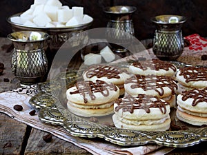 Sandwich cookies with cream decorated with chocolate on a metal platter