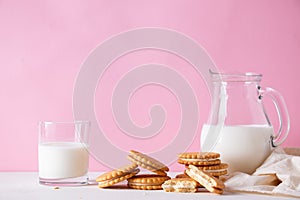 Sandwich cookies and a glass of milk on a pink background. The concept of breakfast and a quick snack