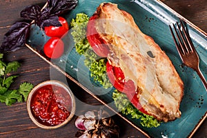 Sandwich with fillet grilled chicken, lettuce, tomatoes, cheese and traditional bread loaf out of the oven on dark background.