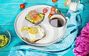 sandwich with fried egg, avocado and salted salmon with a cup of aromatic coffee for breakfast