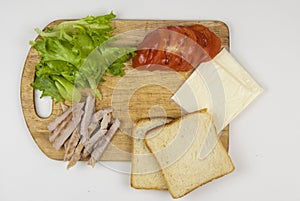 Sandwich with ham, cheese, tomatoes, lettuce, and toasted bread. Above view on white background