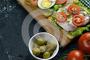 Sandwich with ham and tomatoes on wooden board
