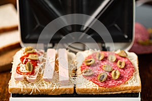 sandwich maker and cooking different sandwiches with sausage, olives, cheese, sausages