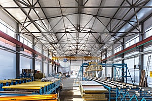 Sandwich manufactory panel production line. Equipment machine tools and roller conveyor in large hangar or workshop