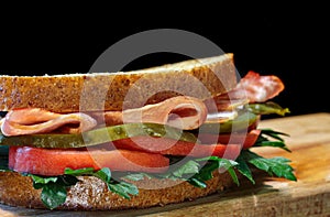 sandwich with meat and vegetables close-up on a black background