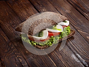 Sandwich with mozzarella, tomatoes, pesto and green salad, on rustic wooden table, nobody