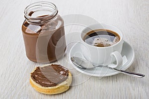 Sandwich with nut-chocolate paste, jar of paste, black coffee