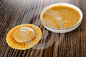 Sandwich with peanut butter, bowl with peanut paste on table