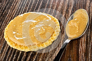 Sandwich with peanut butter, spoon with peanut paste on wooden table