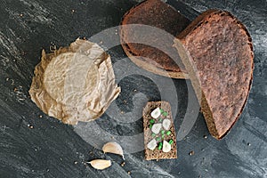 Sandwich of piece bread with onion chives and cloves garlic, sourdough in jar and cuts loaf rye bread, spices on table