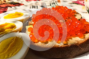 Sandwich with red caviar and boiled eggs, coffee mug. Morning br