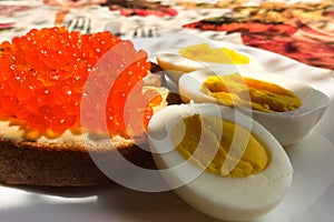 Sandwich with red caviar and boiled eggs, coffee mug. Morning br