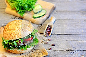 Sandwich with roasted bean cutlet, lettuce, red pepper and cucumber. Delicious sandwich on wooden background with blank space