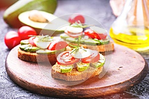 Sandwich with rye bread, avocado, egg, tomato on wooden board