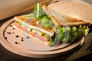 Sandwich with rye brown bread, frash satad and red fish on wooden board