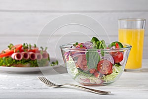 Sandwich with sausage and tomatoes, with salad and orange juice. European breakfast.