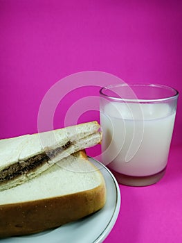 Sandwich served on a plate and fresh milk in a glass. Breakfast menu recommendations.