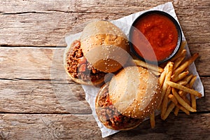 Sandwich Sloppy Joes with sauce and French fries close-up on the