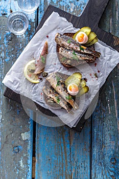 Sandwich with sprats and egg on wooden table, close up