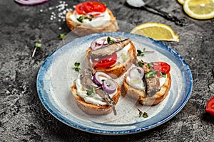 Sandwich with sprats and tomatoes on white plate. Danish cuisine. Food recipe background. Close up